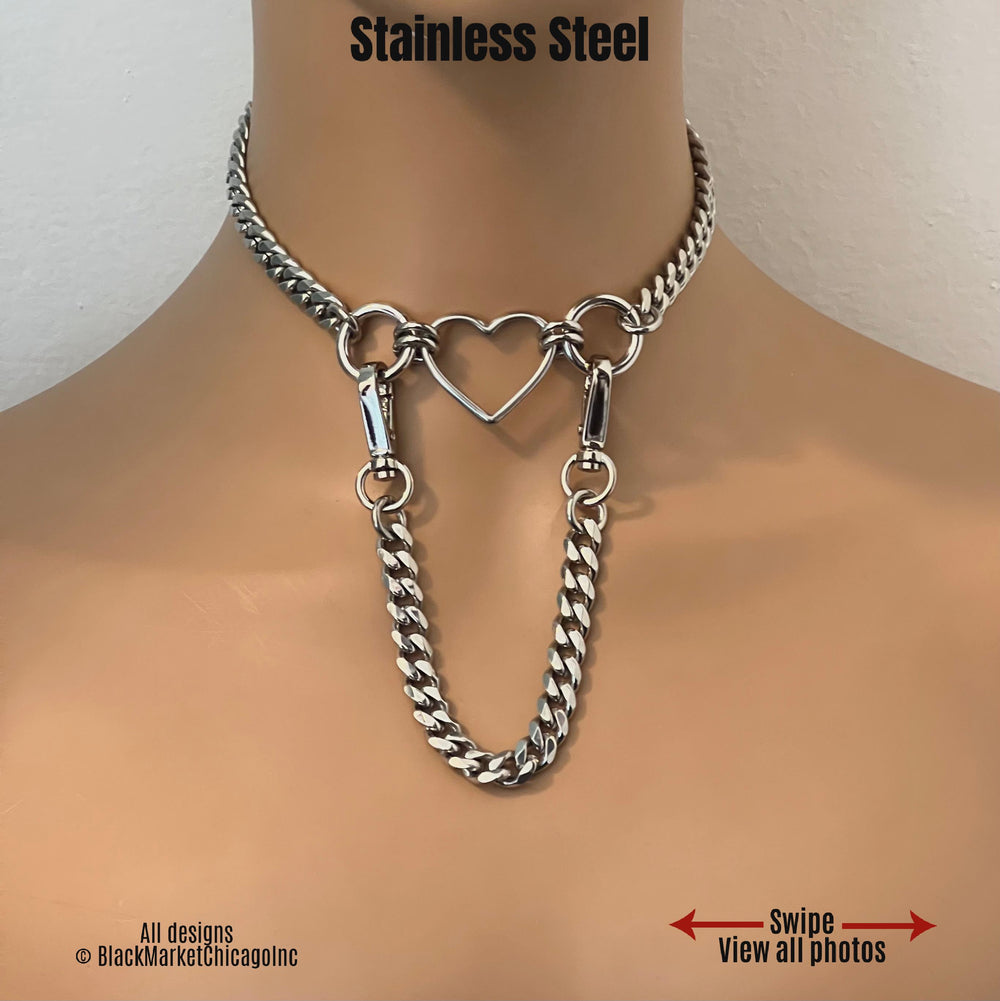 BDSM day collar features all stainless steel; center open heart-shaped ring with 18mm side rings; 8mm sparkly faceted stainless steel chain; detachable 7 inch long chain lead with 360° swivel snaps for versatility. 
Designs ©️BlackMarketChicago Inc