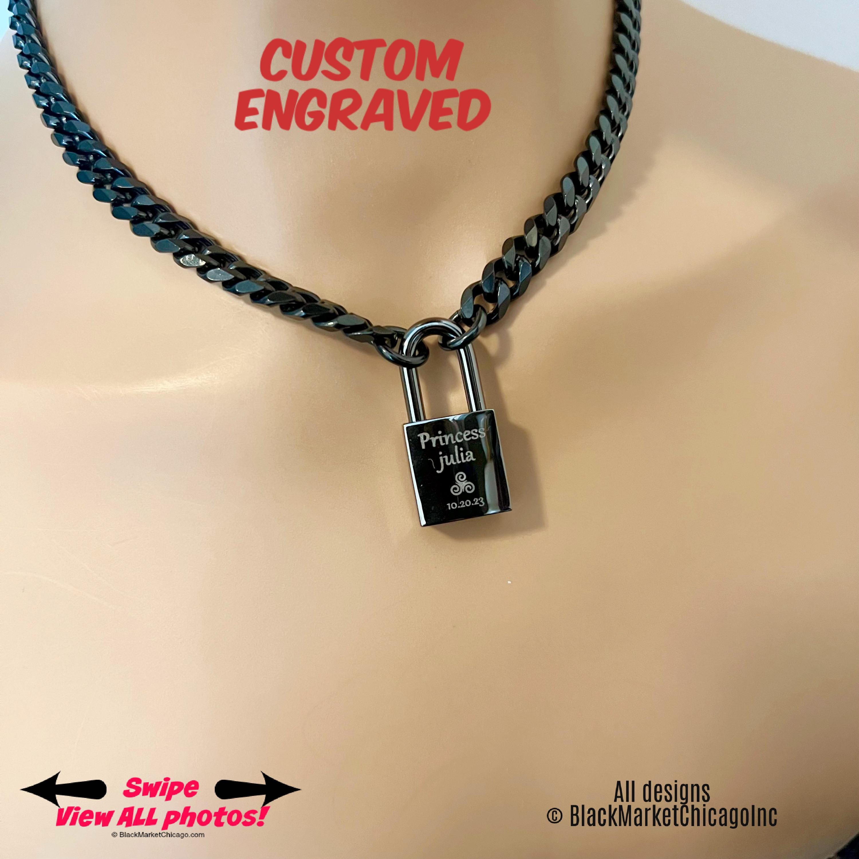 May include: Black metal cuban curb chain necklace with a padlock. The padlock is engraved with the words &#39;Princess Julia&#39; and a symbol, along with the date &#39;10.30.23&#39;.  The necklace is shown on a mannequin. The text &#39;CUSTOM ENGRAVED&#39; is displayed above the necklace.  The text &#39;Swipe View All Photos!&#39; is at the bottom left. The text &#39;All designs © BlackMarketChicagoInc&#39; is at the bottom right.